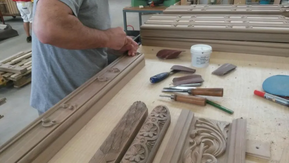 Artigiano al lavoro sull'intaglio di una cornice in legno